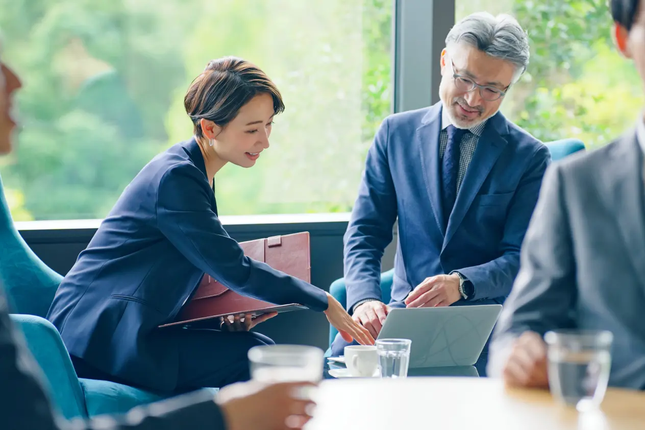 Photo of a man and a woman conversing while looking at a PC in an office.